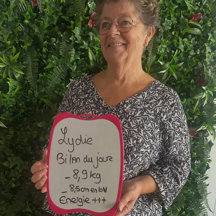 Lydie avec son ardoise : Bilan du jour : −8,9 kg, −8,5 cm en 10 visites. Énergie +++.