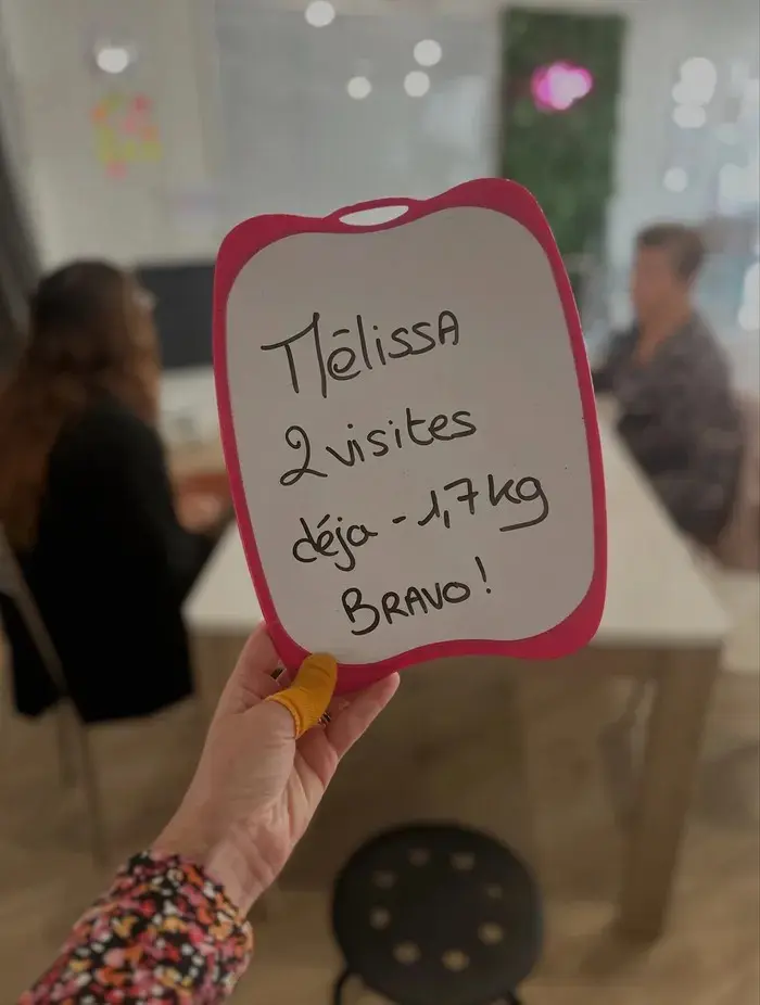 Mélissa avec son ardoise : 2 visites : déjà −1,7 kg. Bravo !